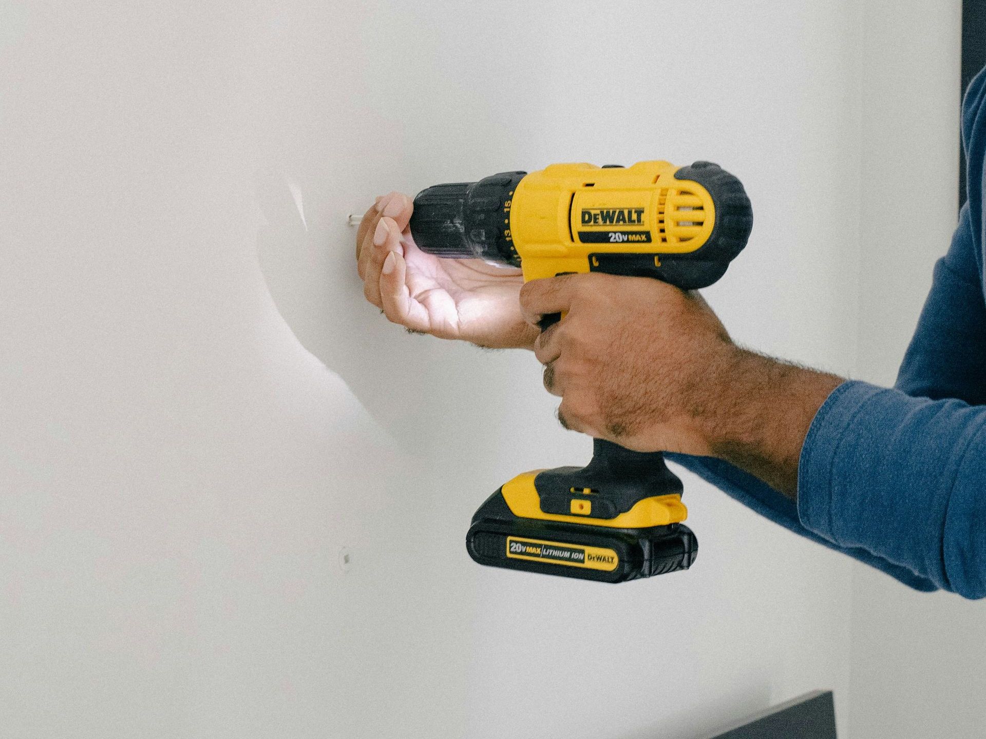 a man is holding a drill and a cordless drill